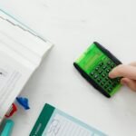 A student uses a green calculator to solve math equations from a textbook on a desk.